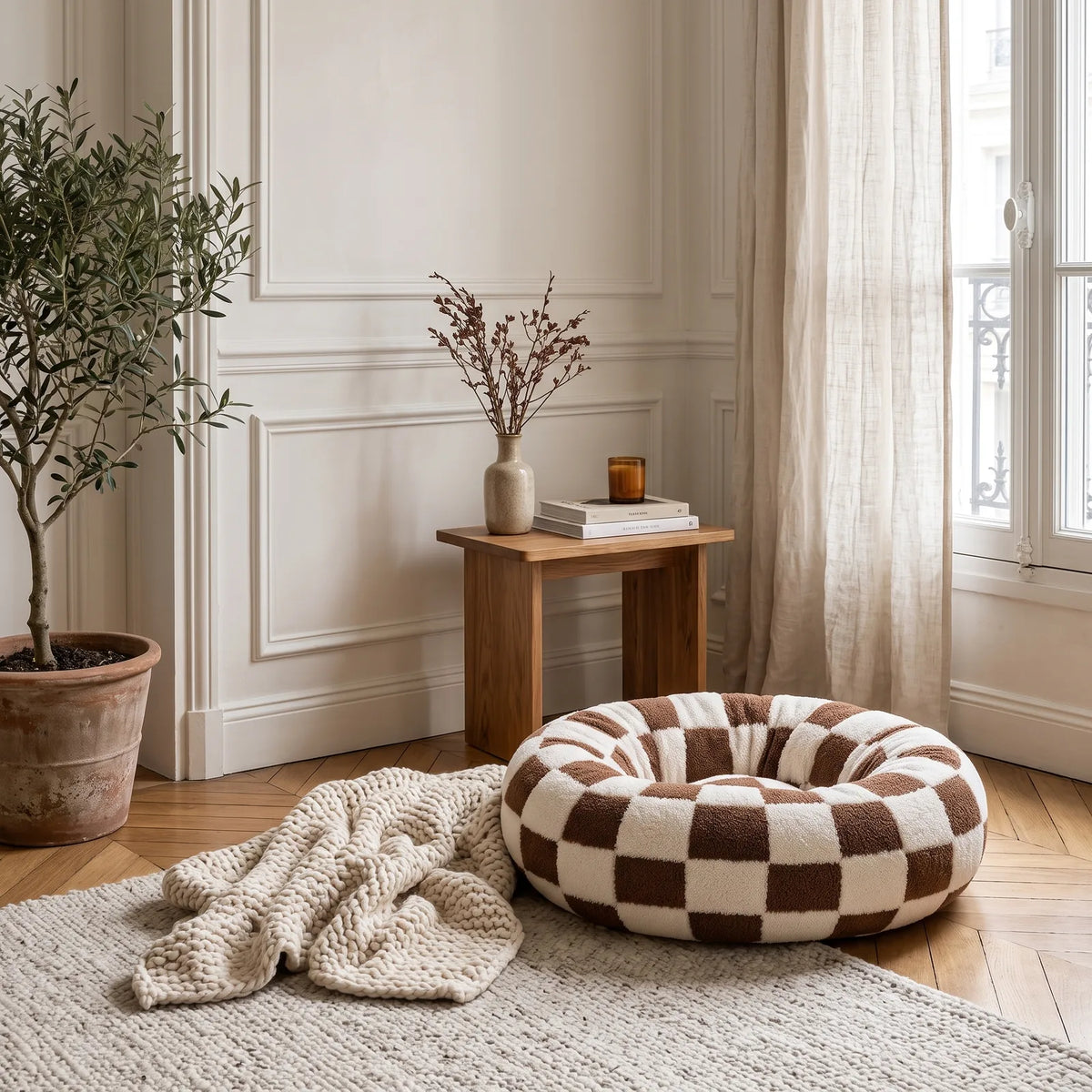 Panier rond anti-stress damier chocolat installé dans un coin déco avec plaid et plante