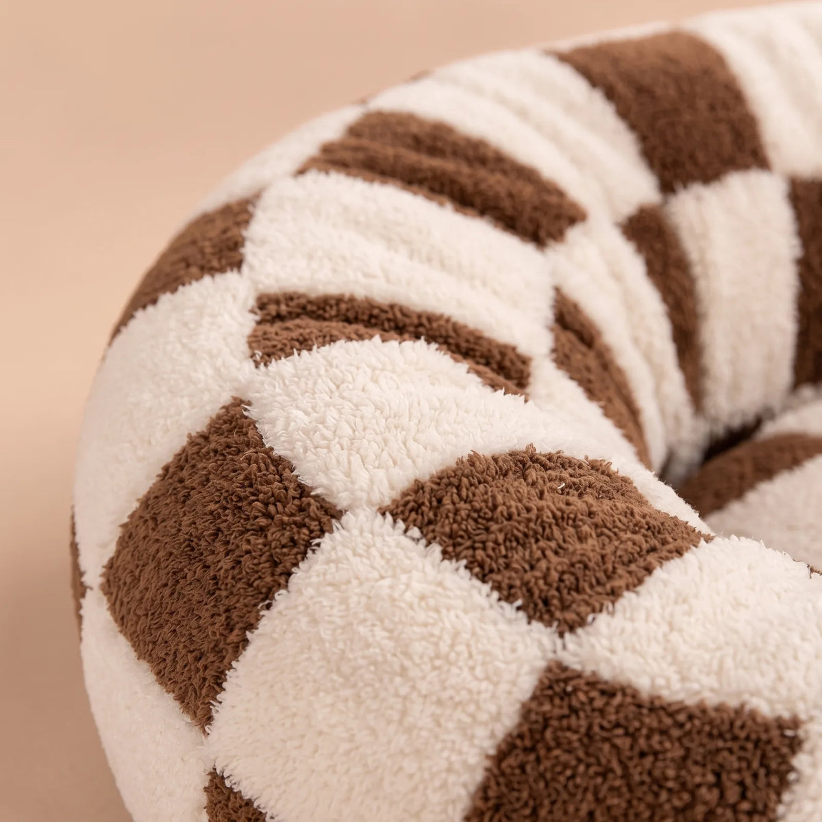 Gros plan sur le tissu doux et le rebord rembourré du panier anti-stress à damier marron et crème