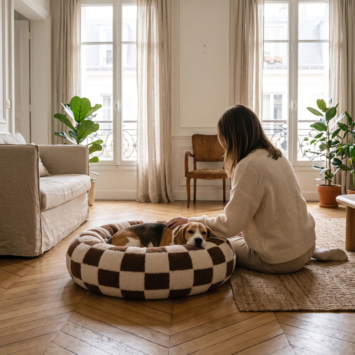 Maîtresse caressant son beagle couché dans un panier anti-stress damier chocolat