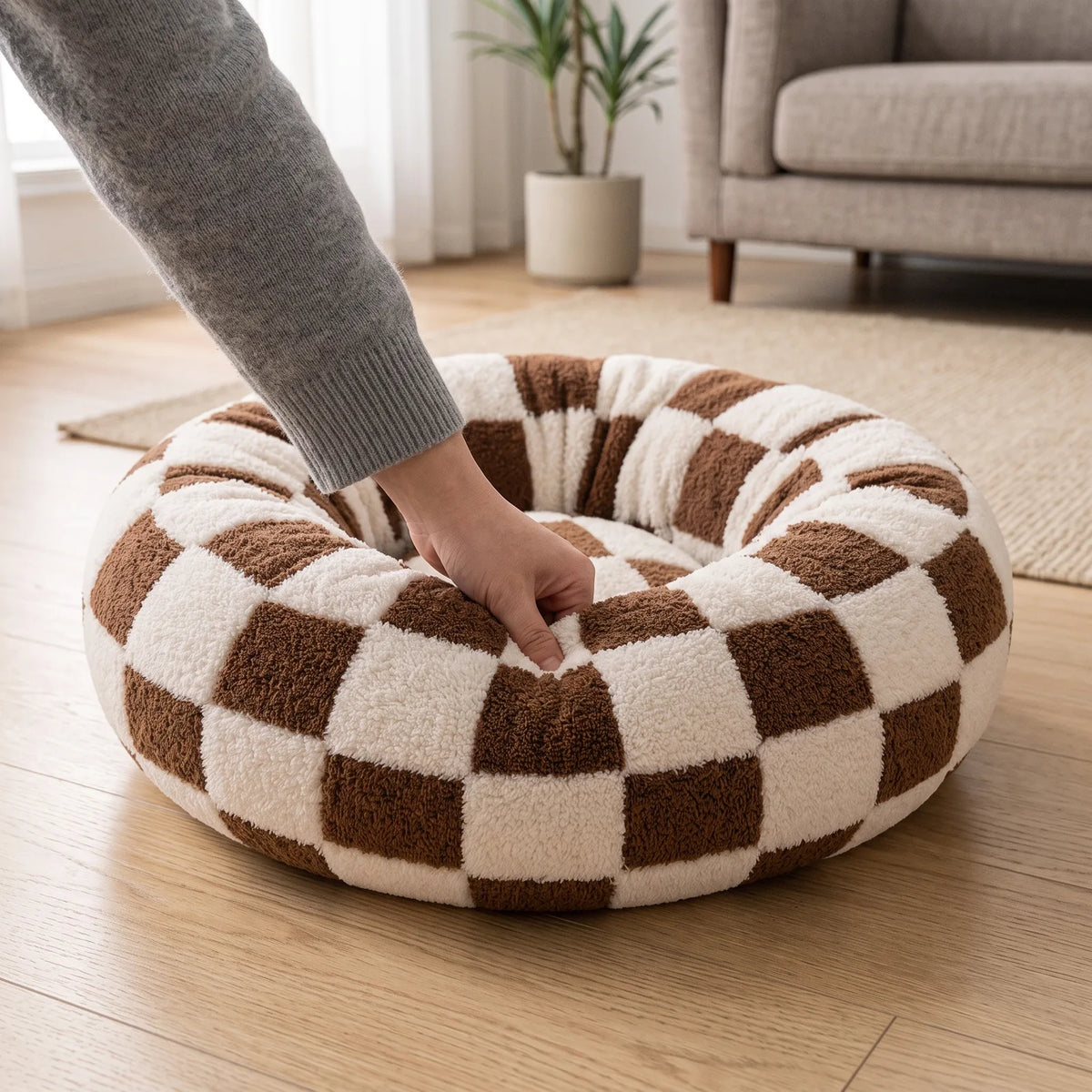 Main pressant le rebord doux et moelleux du panier anti-stress damier marron et crème