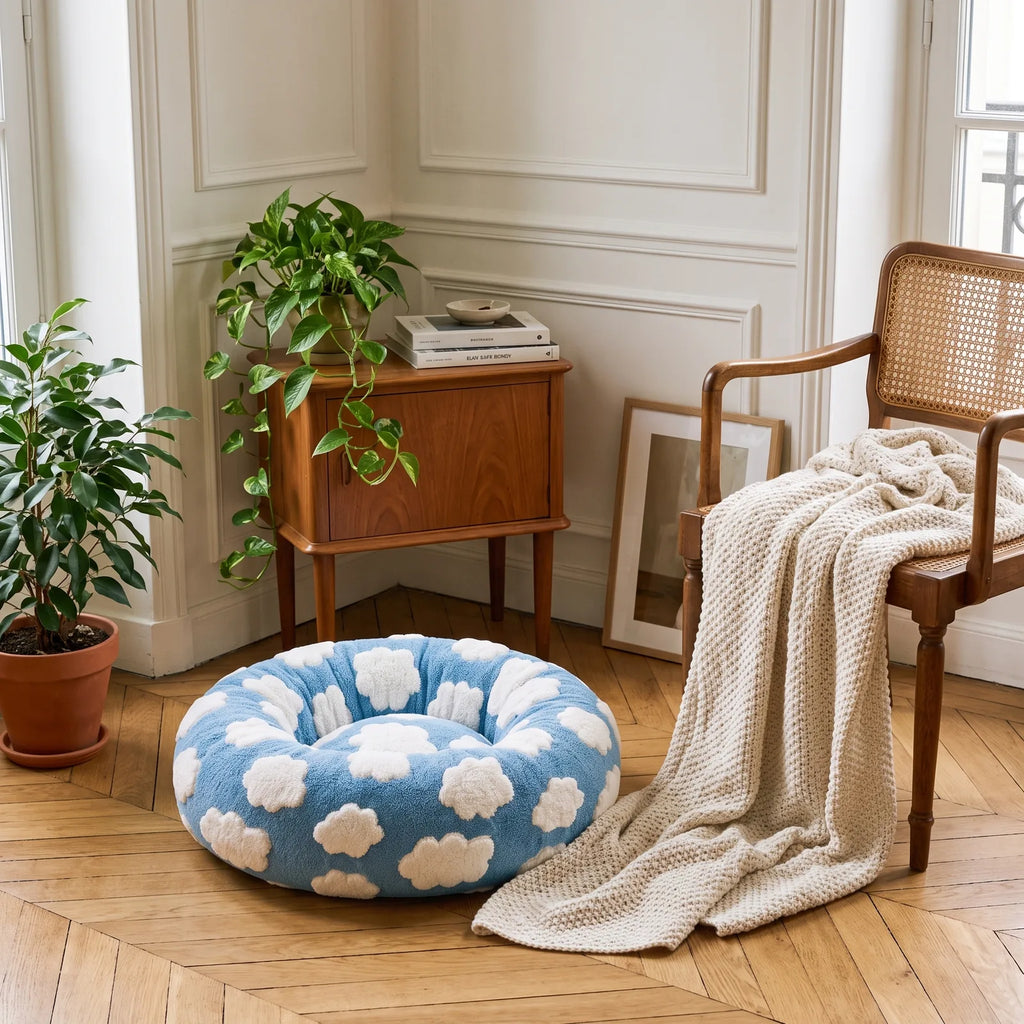 Panier rond anti-stress bleu à motif nuages installé dans un coin déco avec plaid et plante