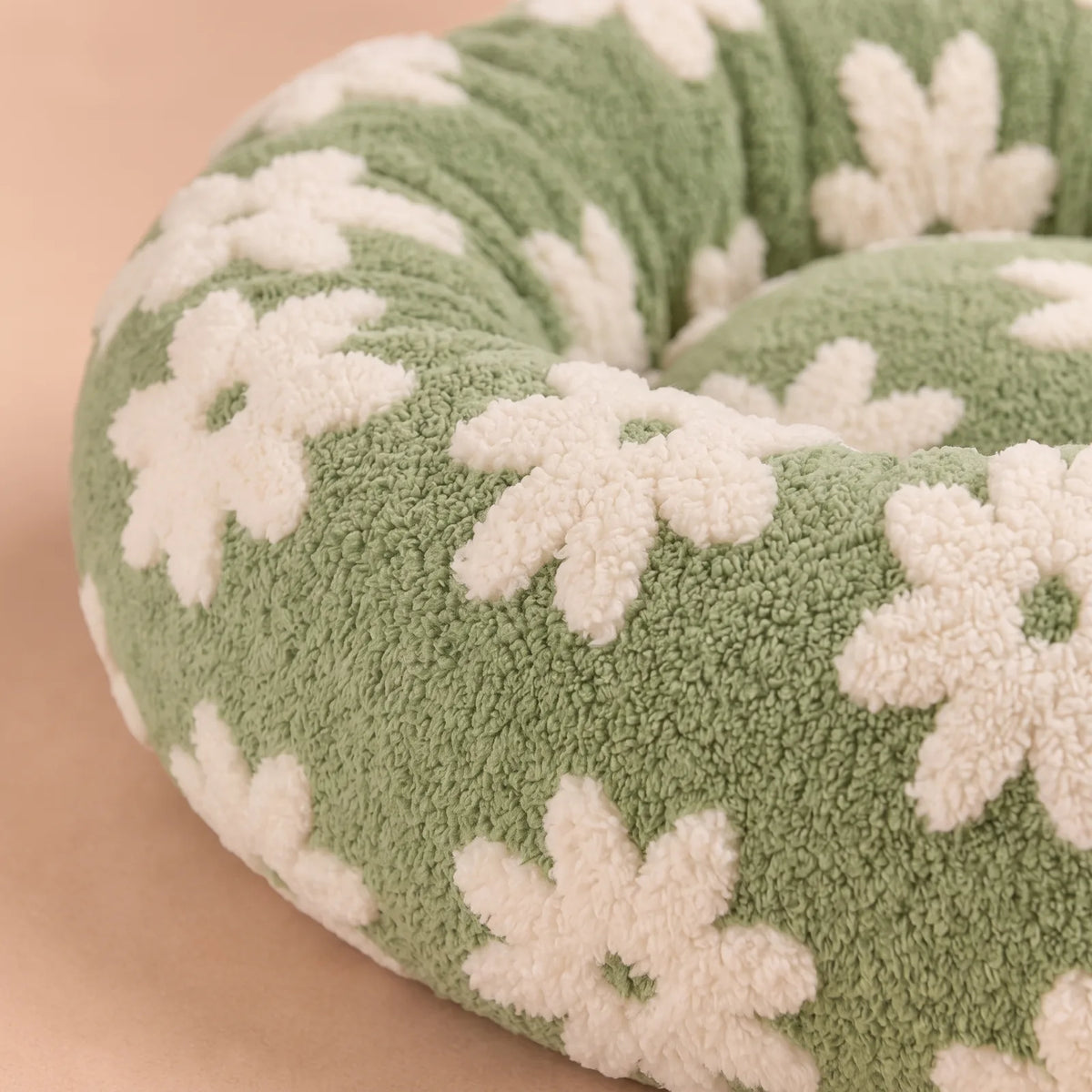 Gros plan sur le tissu doux bouclé et le rebord rembourré du panier anti-stress vert à pâquerettes