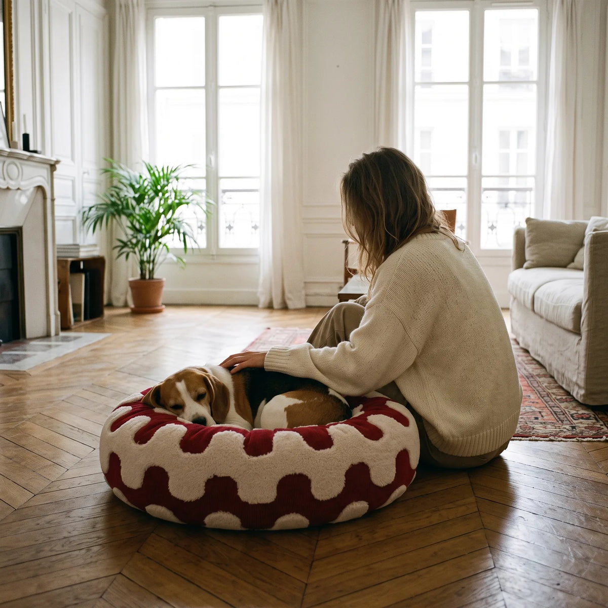 Maîtresse caressant son beagle couché dans un panier anti-stress rouge